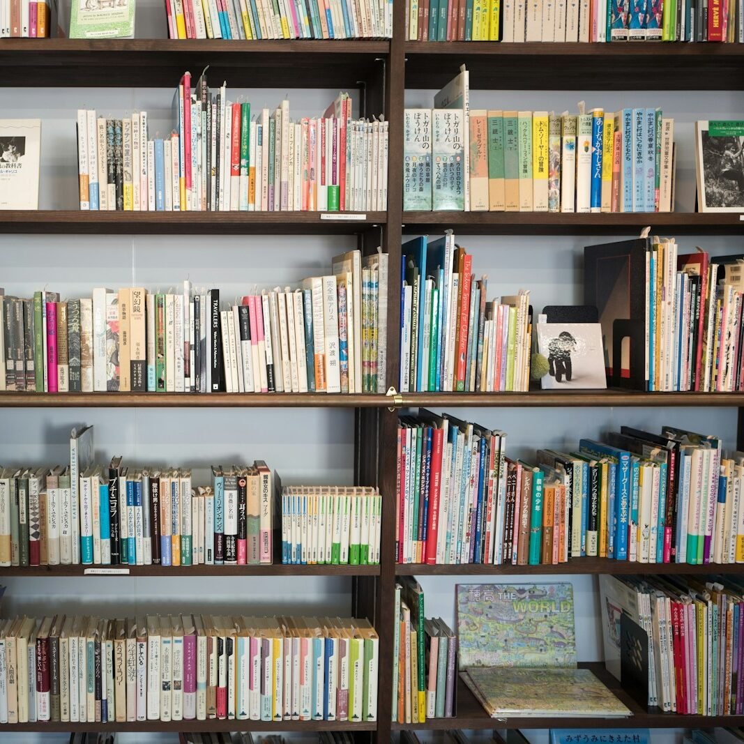 assorted books on brown wooden shelf at daytime