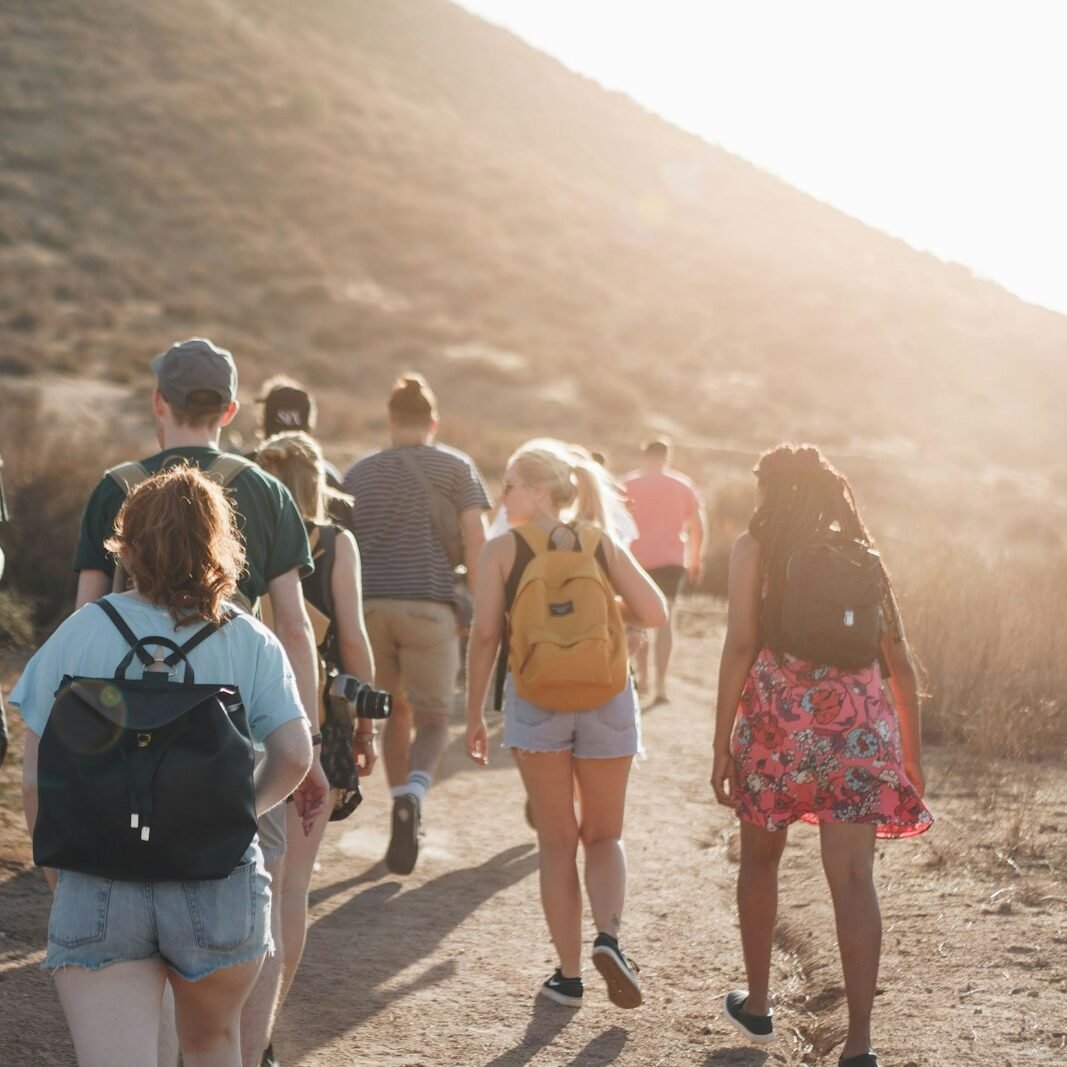 people walking on dirt road near mountain during daytime